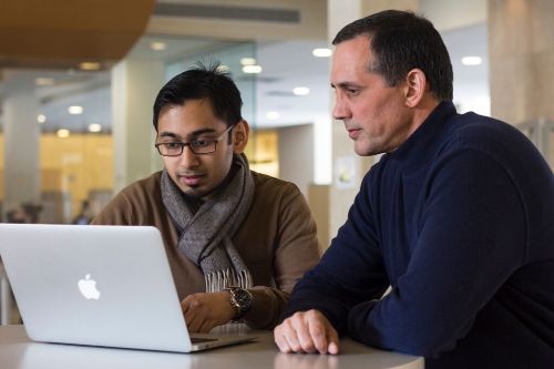 Student and faculty mentor working on laptop